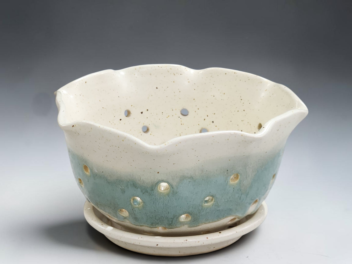 Handmade pottery berry bowl in cream glaze with aqua band and matching drip tray