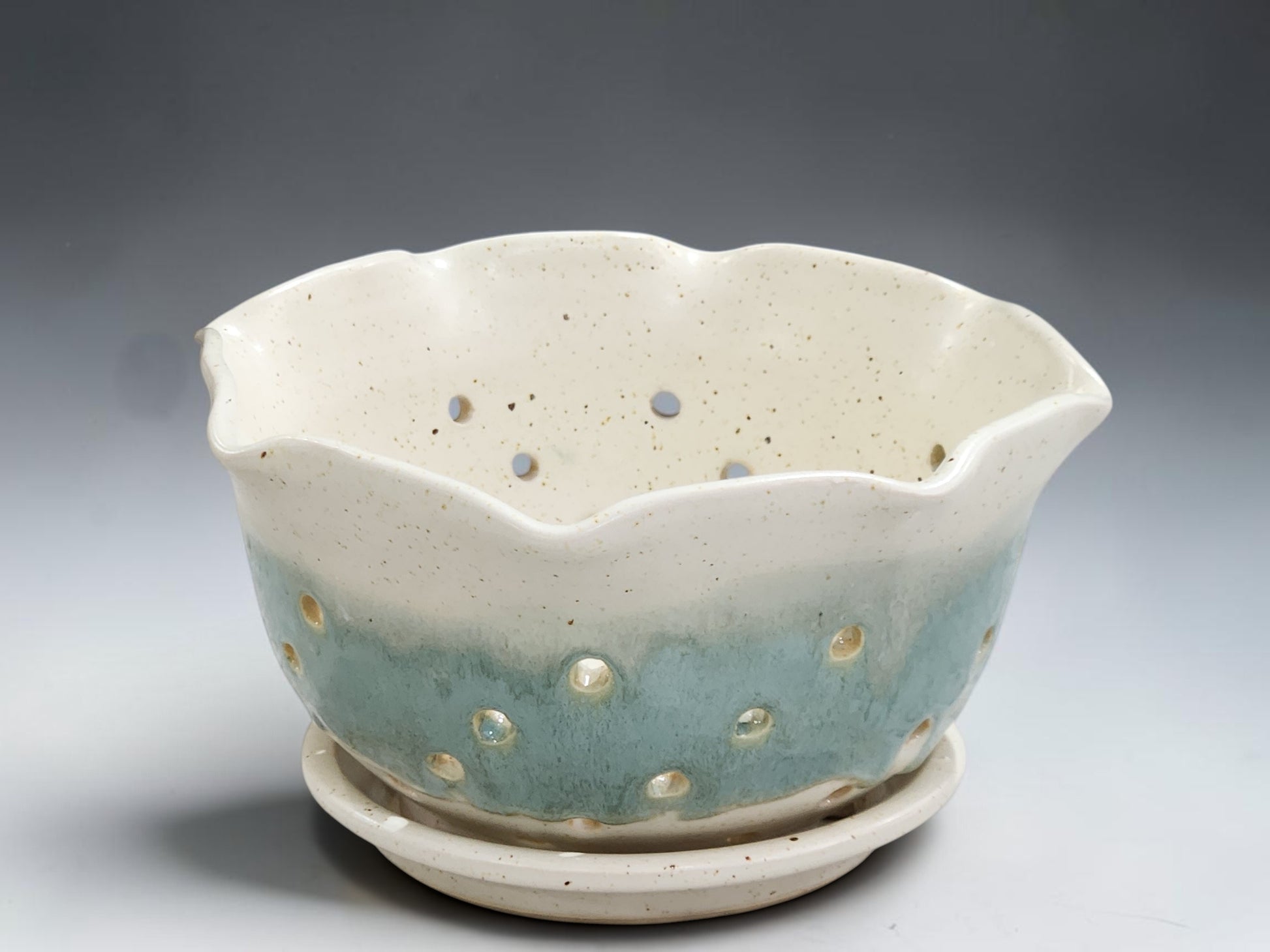 Handmade pottery berry bowl in cream glaze with aqua band and matching drip tray