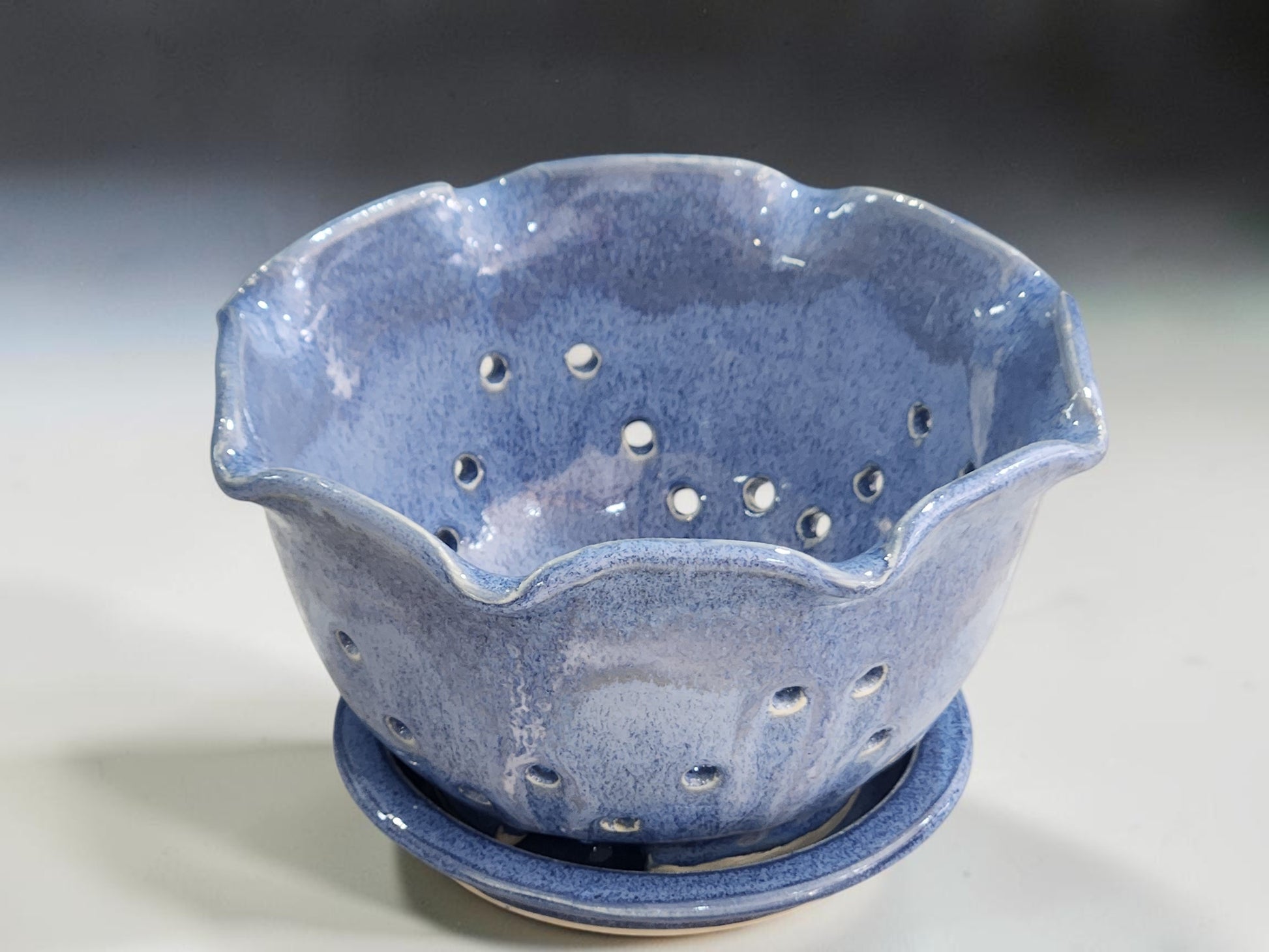 Blue ceramic colander bowl with drainage holes and saucer