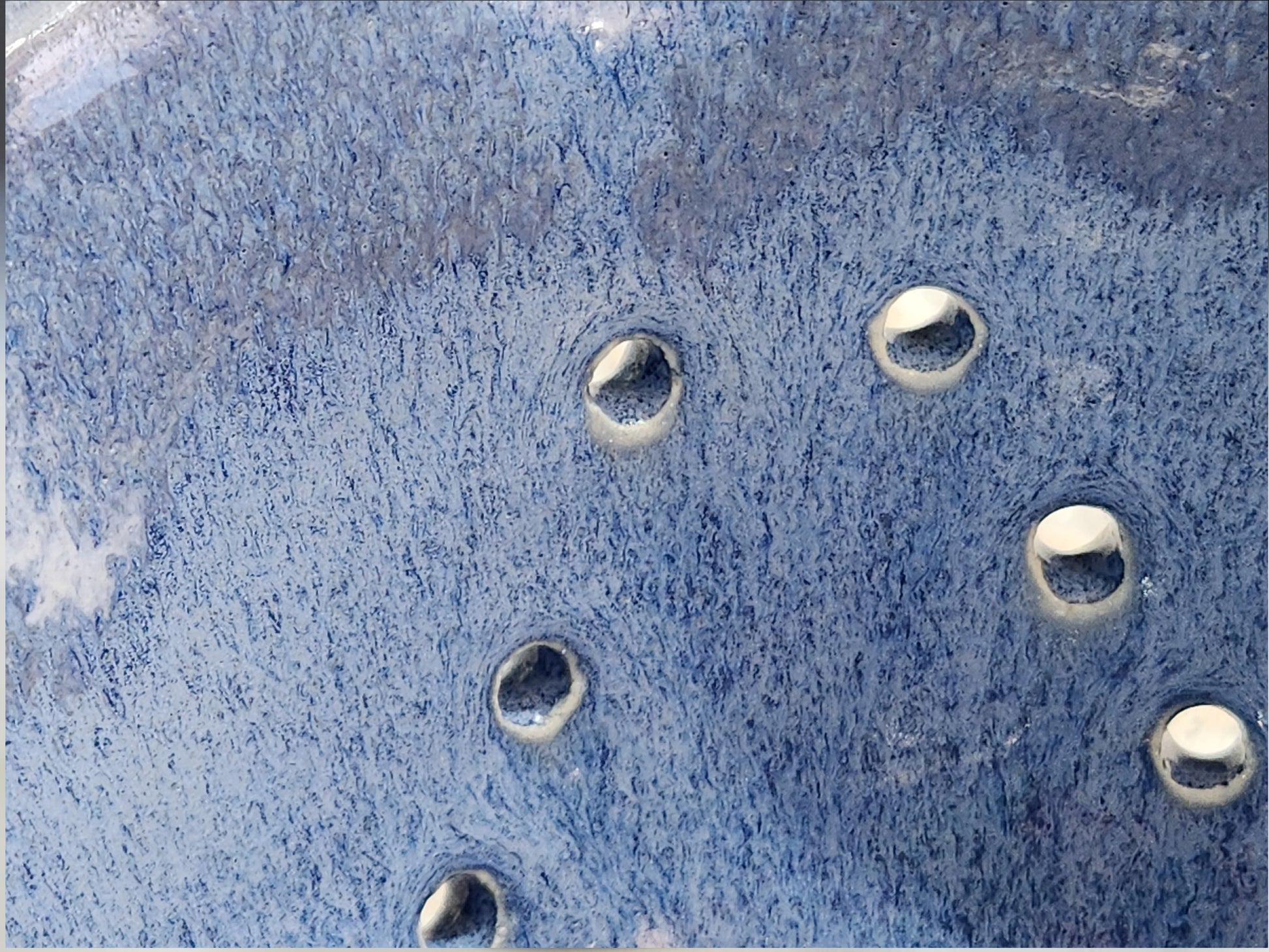 Close-up of handmade blue berry bowl with decorative wavy rim