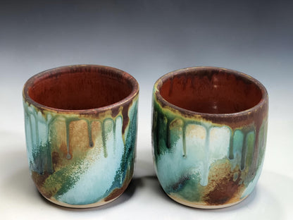 Wheel thrown ceramic tumbler with flowing turquoise, amber and brown glaze