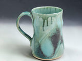 Handmade ceramic coffee mug in Bush Creek glaze, photographed on a professional grey gradient studio background