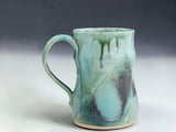 Handmade ceramic mug with curved handle, glossy Bush Creek glaze and natural handmade variation on grey background