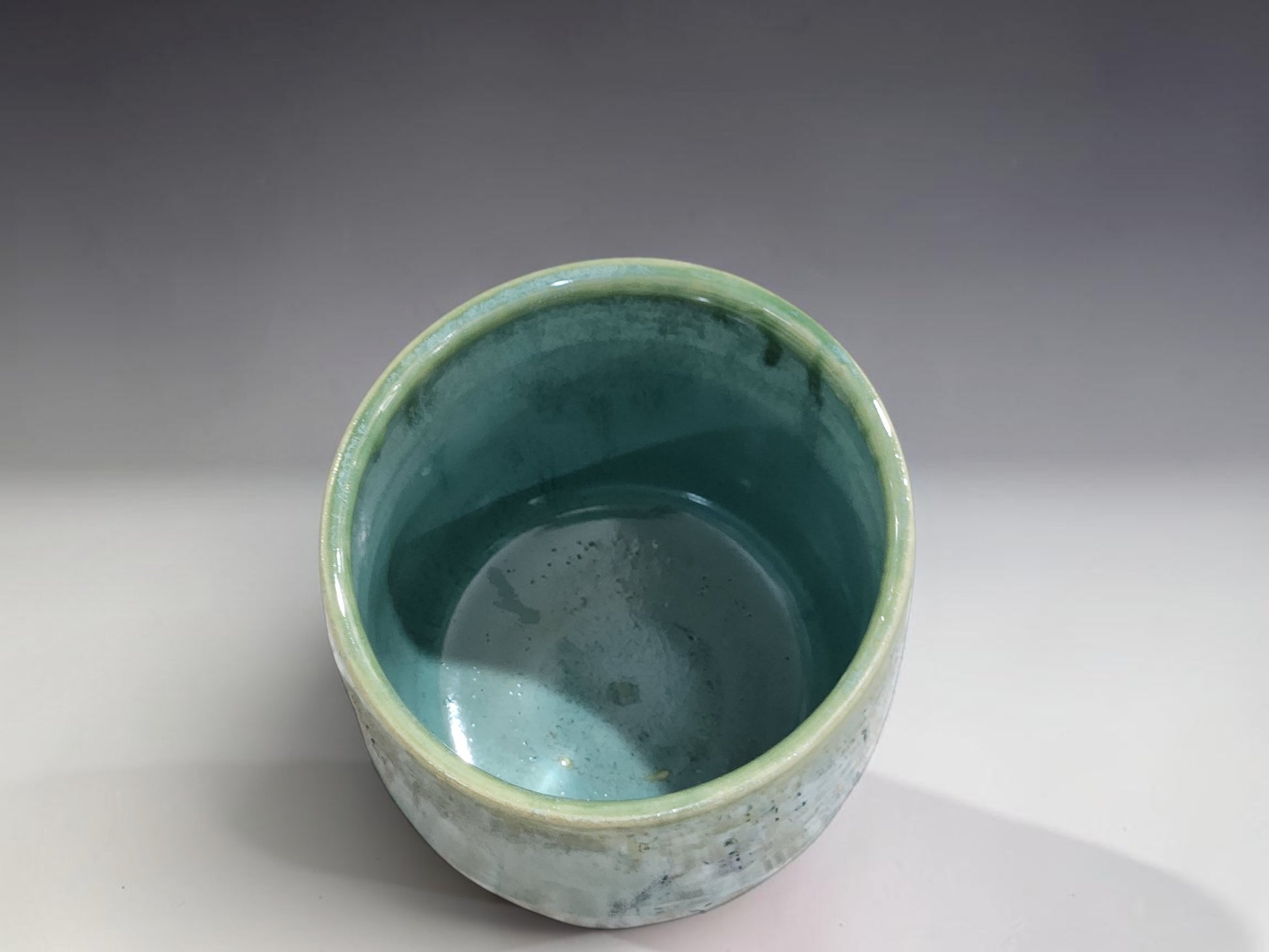 Handmade pottery tumbler in misty blue-green glaze with darker green drips and glossy finish