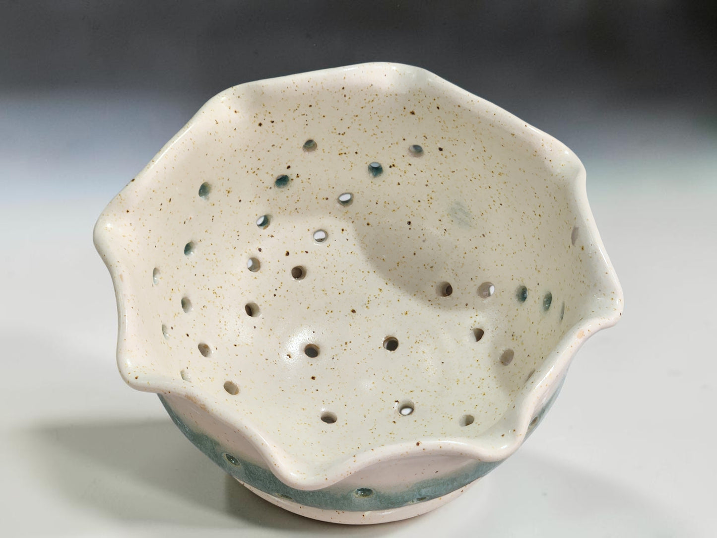 Handmade stoneware berry bowl with drainage holes and matching saucer