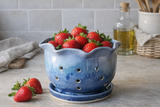 Handmade ceramic strawberry bowl filled with fresh strawberries on a kitchen countertop, blue glazed pottery berry bowl