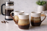 Three handmade ceramic mugs on a kitchen countertop with a coffee pot, Australian stoneware pottery