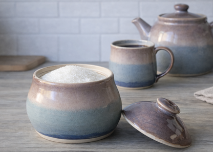 Handmade ceramic sugar bowl with lid in soft blue and beige glaze on kitchen benchtop