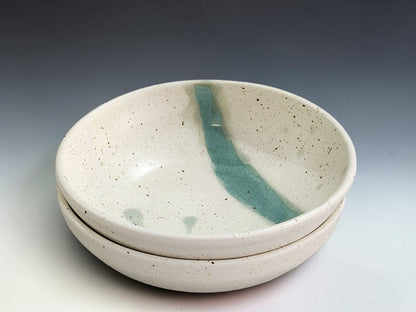Handmade pottery pasta bowl with soft cream speckled glaze and green interior accent