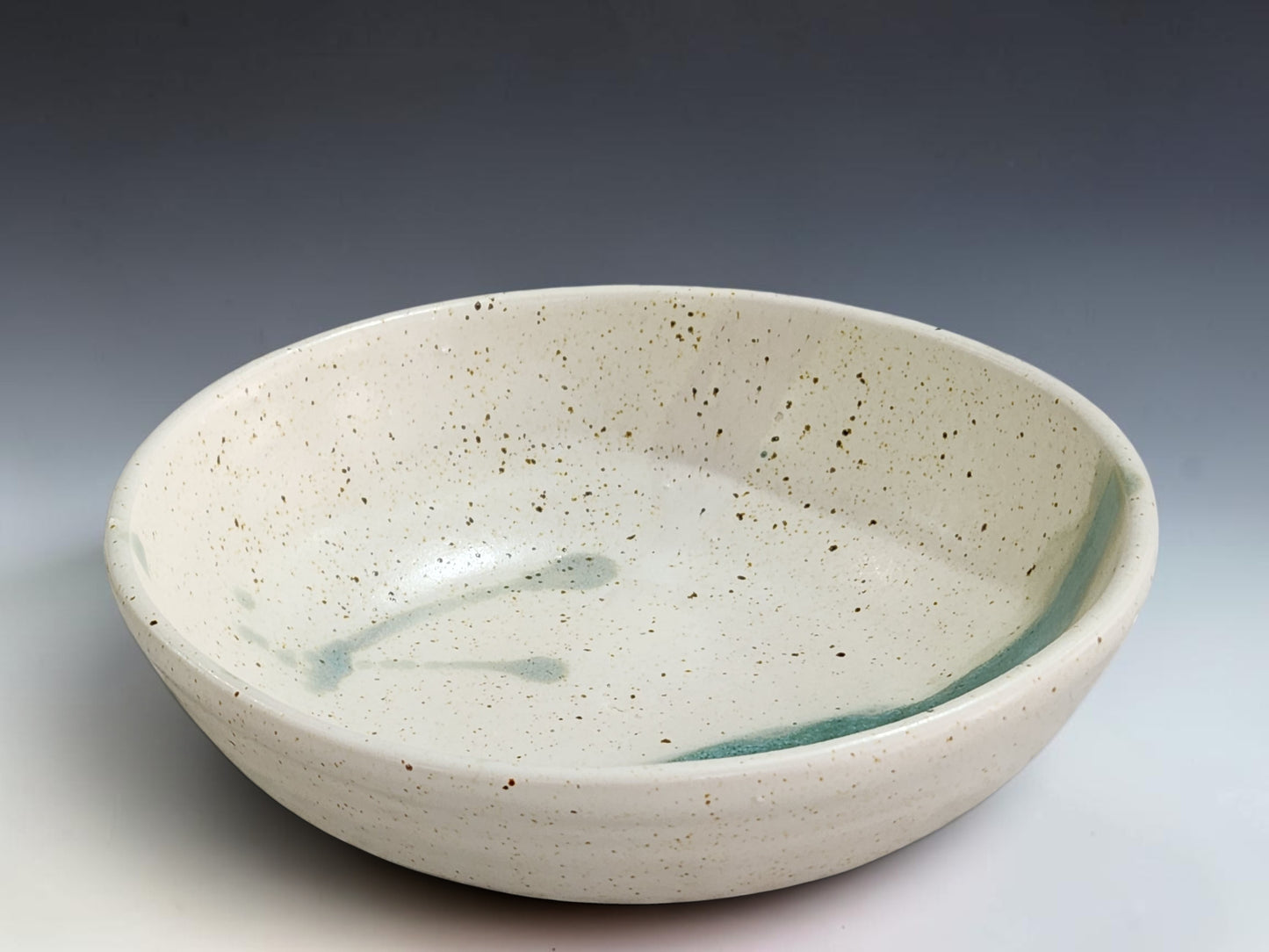 Handmade pottery serving bowl in neutral cream glaze with soft green stripe detail