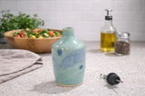 Handmade ceramic oil bottle with separate stainless steel pour spout in lifestyle kitchen setting
