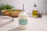 Cream and green handmade pottery oil bottle on kitchen counter in lifestyle setting