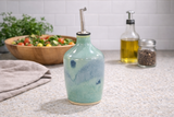 : Handmade green and blue pottery oil bottle on kitchen counter with salad bowl