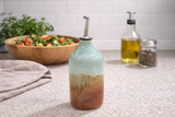 Handmade pottery oil bottle on kitchen counter with salad bowl in lifestyle setting