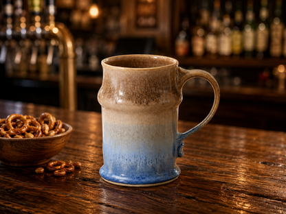 Wheel-thrown pottery stein displayed on a wooden bar with pretzels