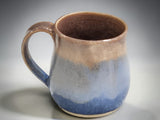 Handmade ceramic mug with flowing blue glaze and comfortable handle