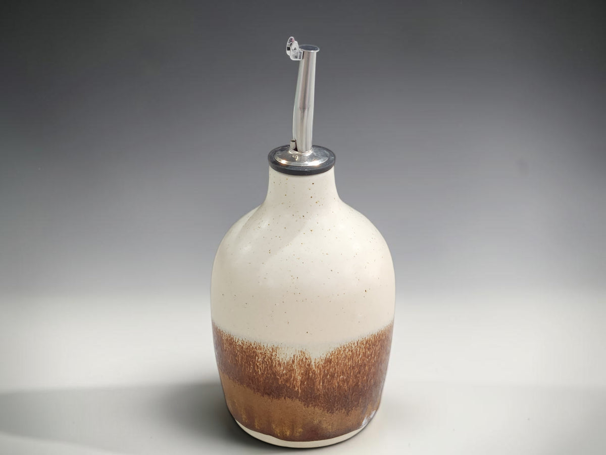 Handmade Australian pottery oil bottle beside olive oil dish