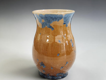 A home decor vase with blue crystals on an amber background.

