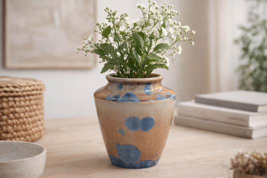 Handmade crystalline ceramic vase in amber glaze with blue crystals on a soft grey studio background