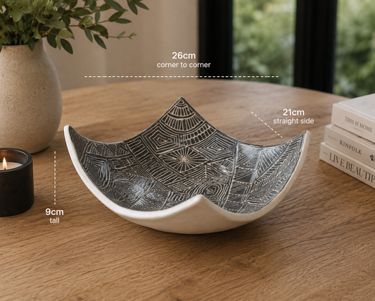 Hero image of black and white carved drape bowl displayed on rustic timber table with modern home décor accents