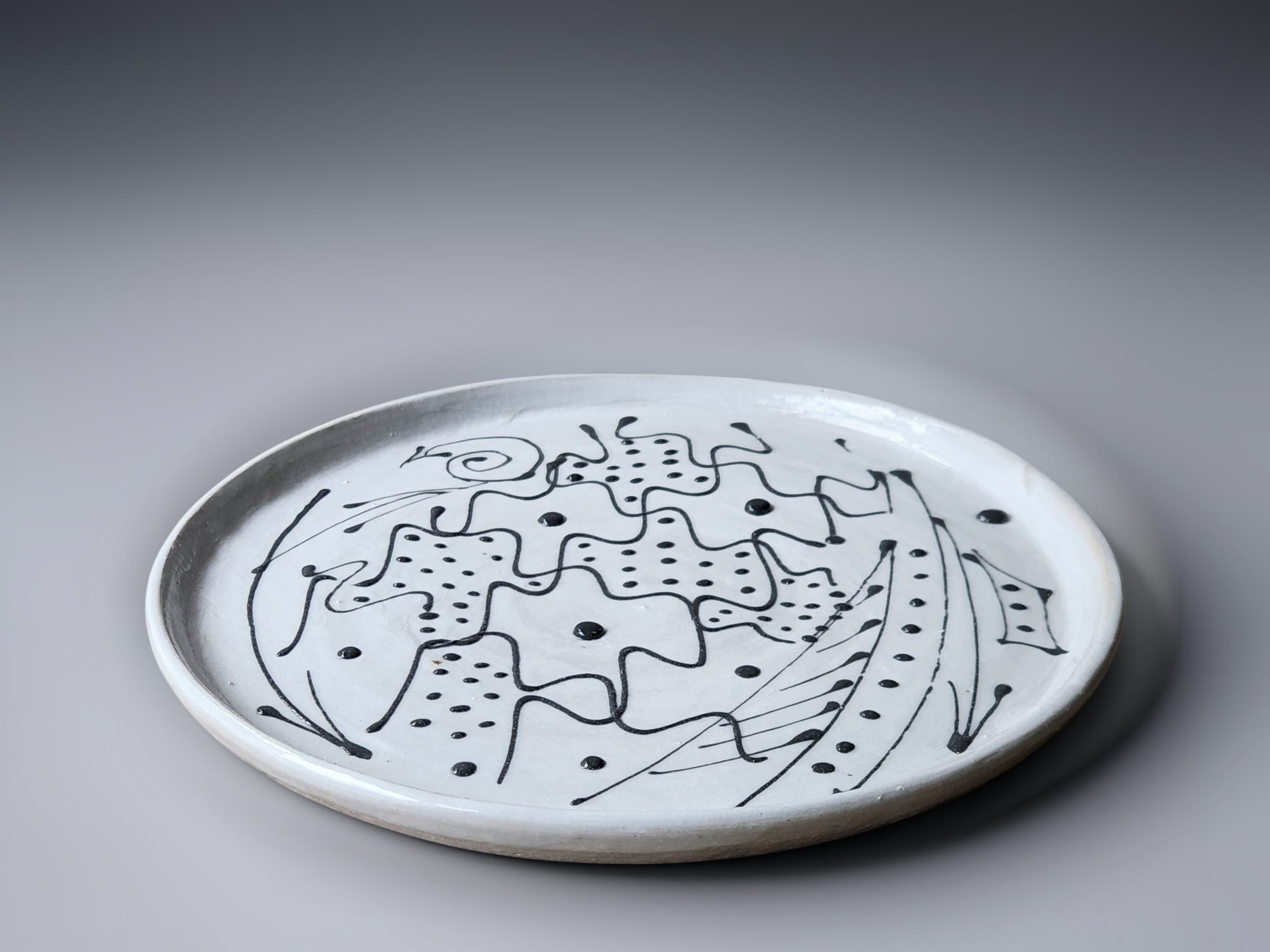 Ceramic plate with black abstract design on a gray background