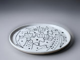 Ceramic plate with black abstract design on a gray background