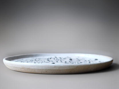 side view of a handmade stoneware plate with white and black slip decoration