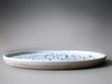 side view of a handmade stoneware plate with white and black slip decoration