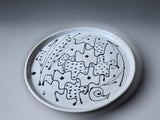 An abstract black slip design on a white pottery plate handmade in Australia.