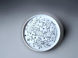 top view of a handmade pottery plate made with a white slip and black decoration.