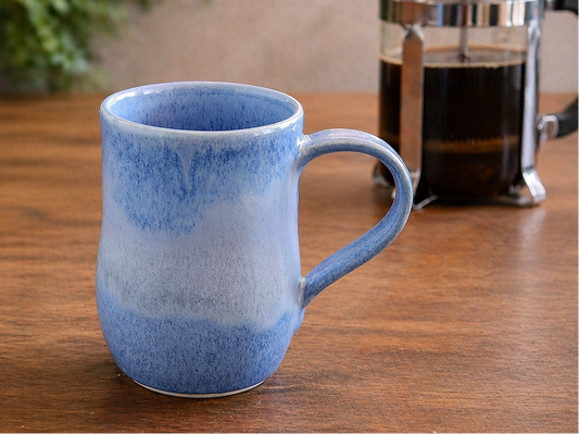 image of blue handmade mug on timber benchtop with French coffee plunger
