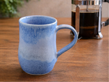 image of blue handmade mug on timber benchtop with French coffee plunger