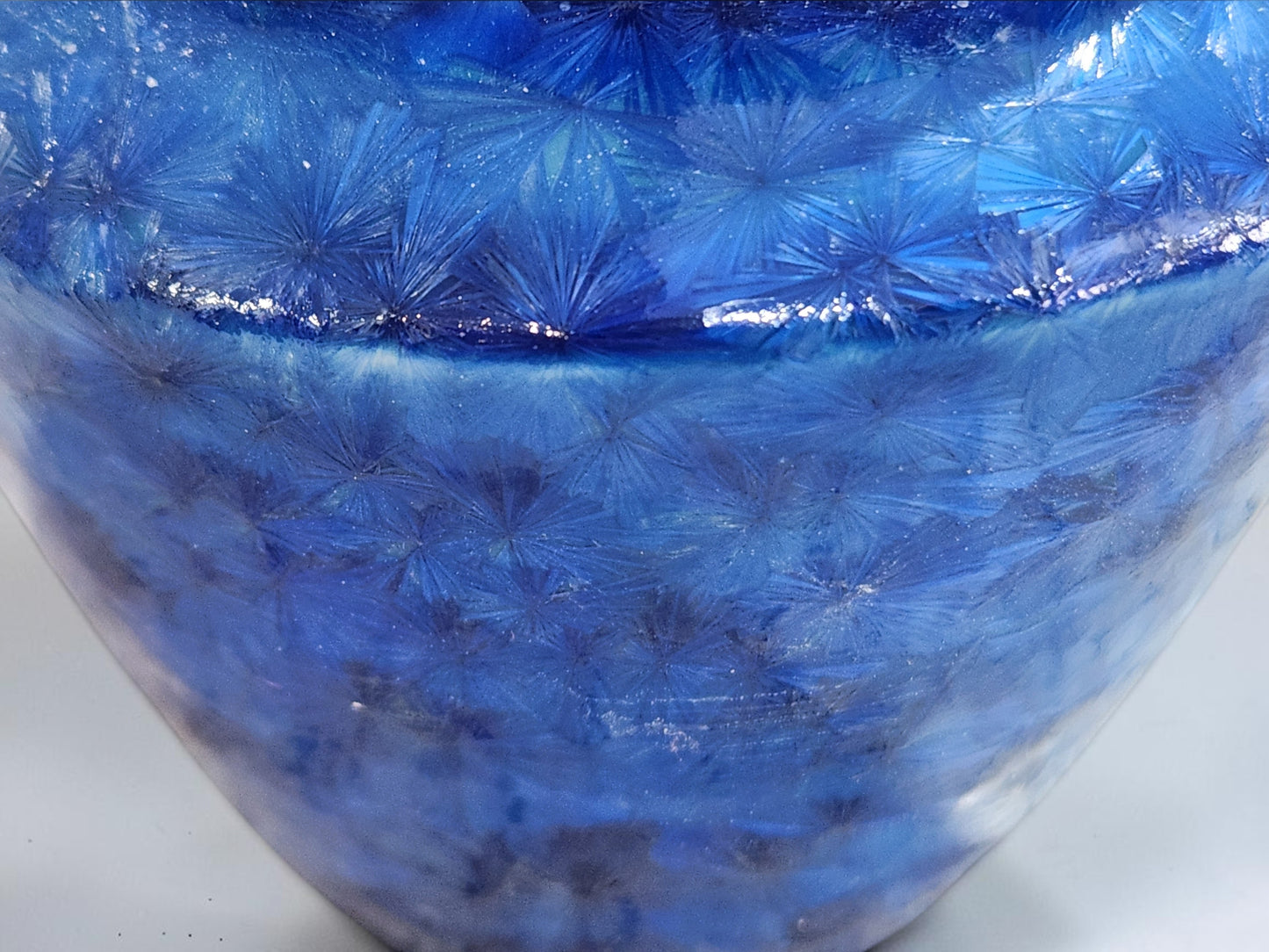 Close-up of naturally formed crystals across a rich blue porcelain glaze