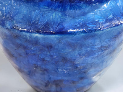 Close-up of naturally formed crystals across a rich blue porcelain glaze