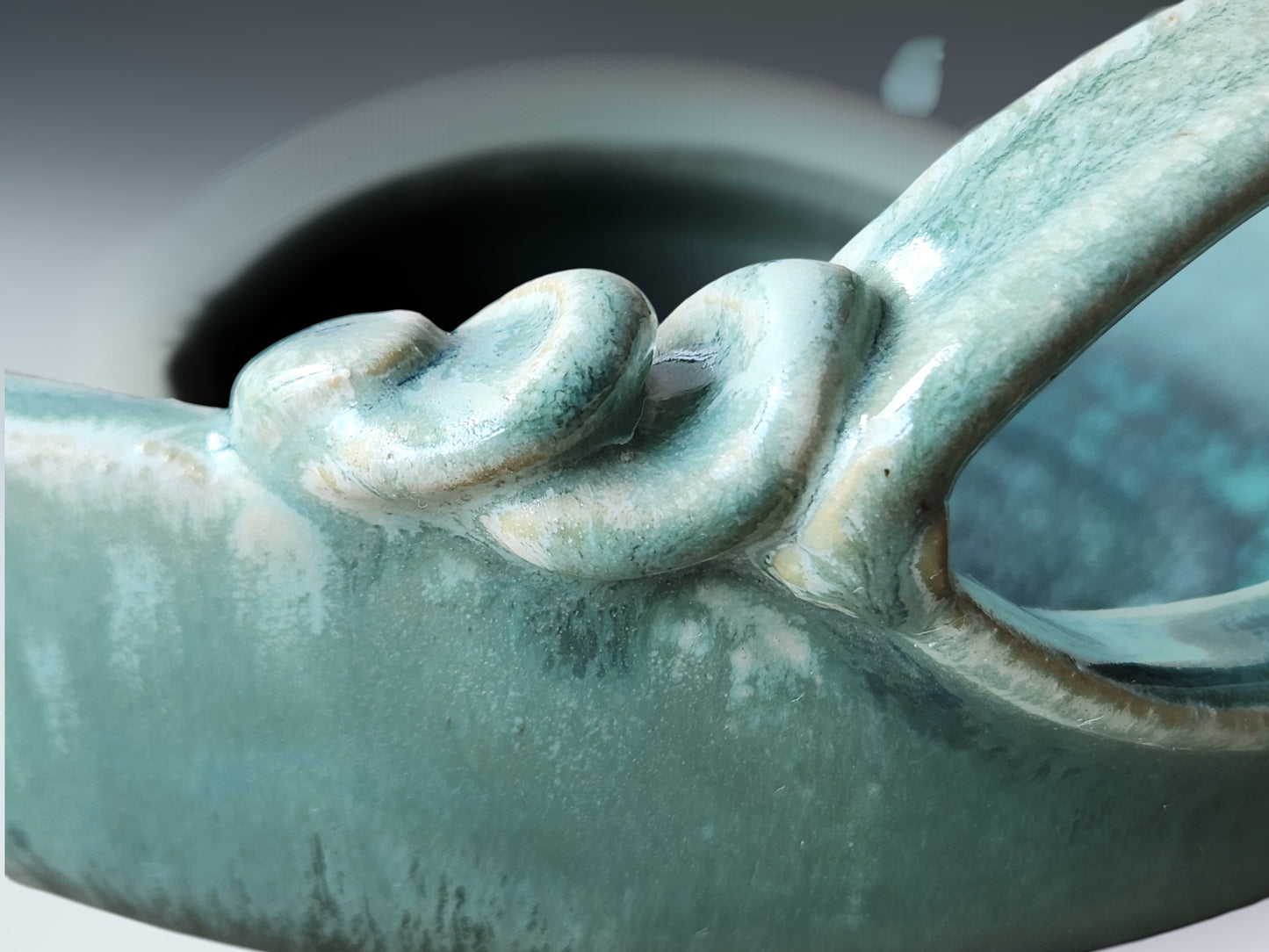 Close-up of turquoise ceramic glaze showing layered texture and flowing artisan finish