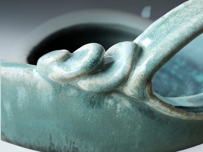 Close-up of turquoise ceramic glaze showing layered texture and flowing artisan finish