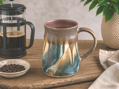 Hero image of handmade Bush Creek Earth pottery mug in rustic coffee setting with French press