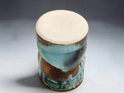 Handmade pottery mug on grey studio background showing handle, glaze movement and red brown lining