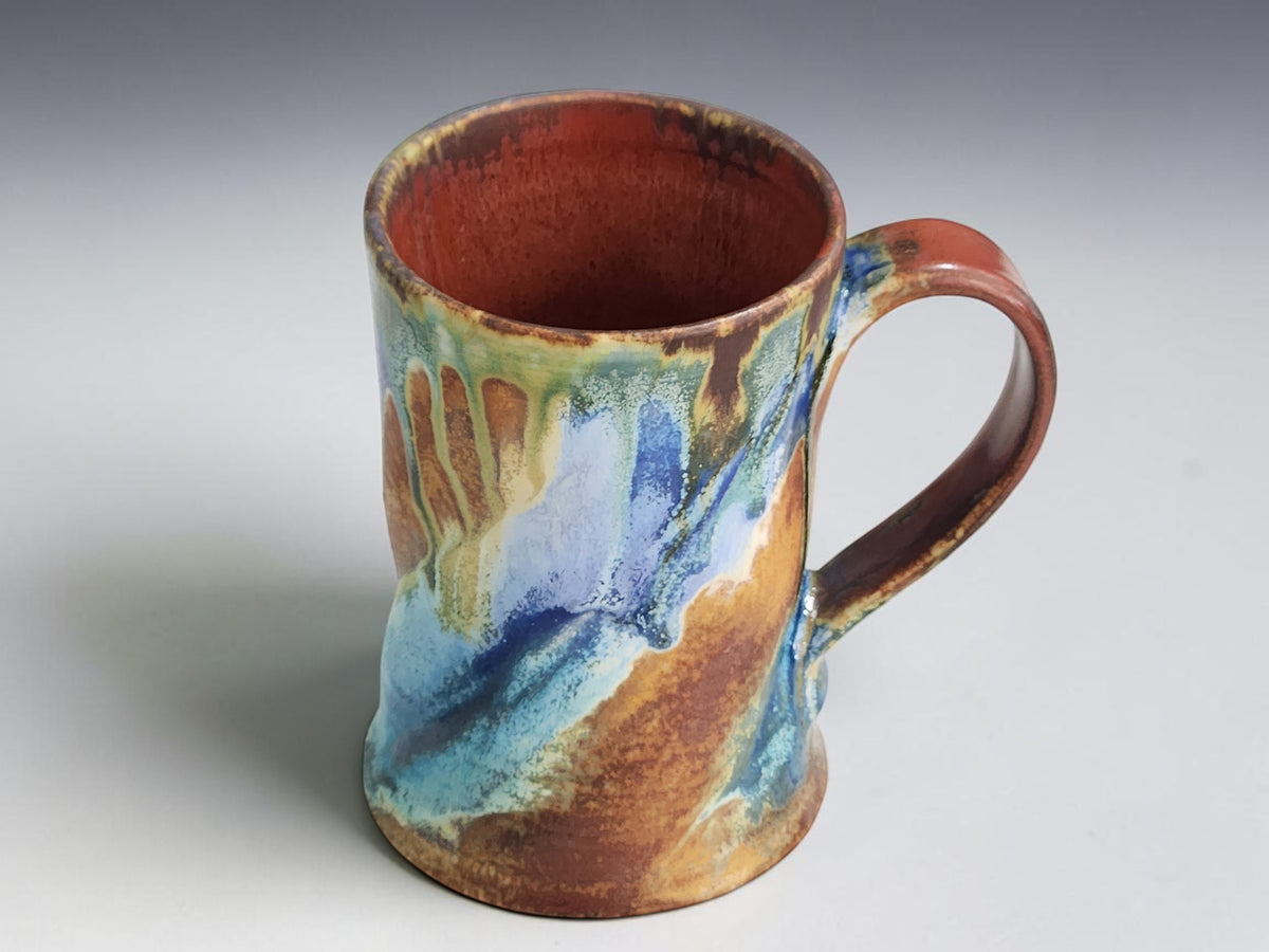 Handmade Bush Creek pottery mug with flowing blue, green and earthy brown glaze.