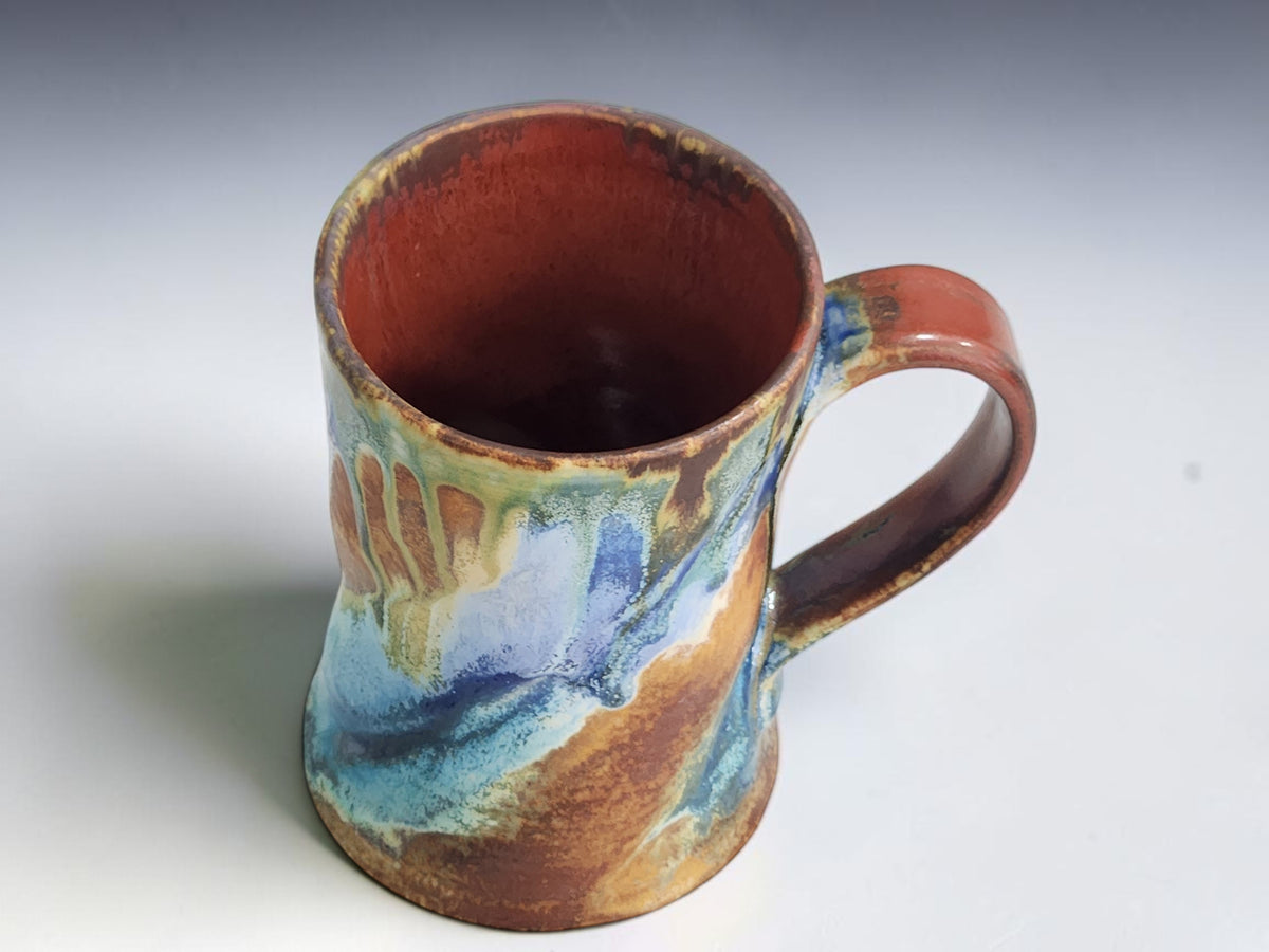 Tall handmade mug with sweeping pale blue glaze and warm ochre brown accents