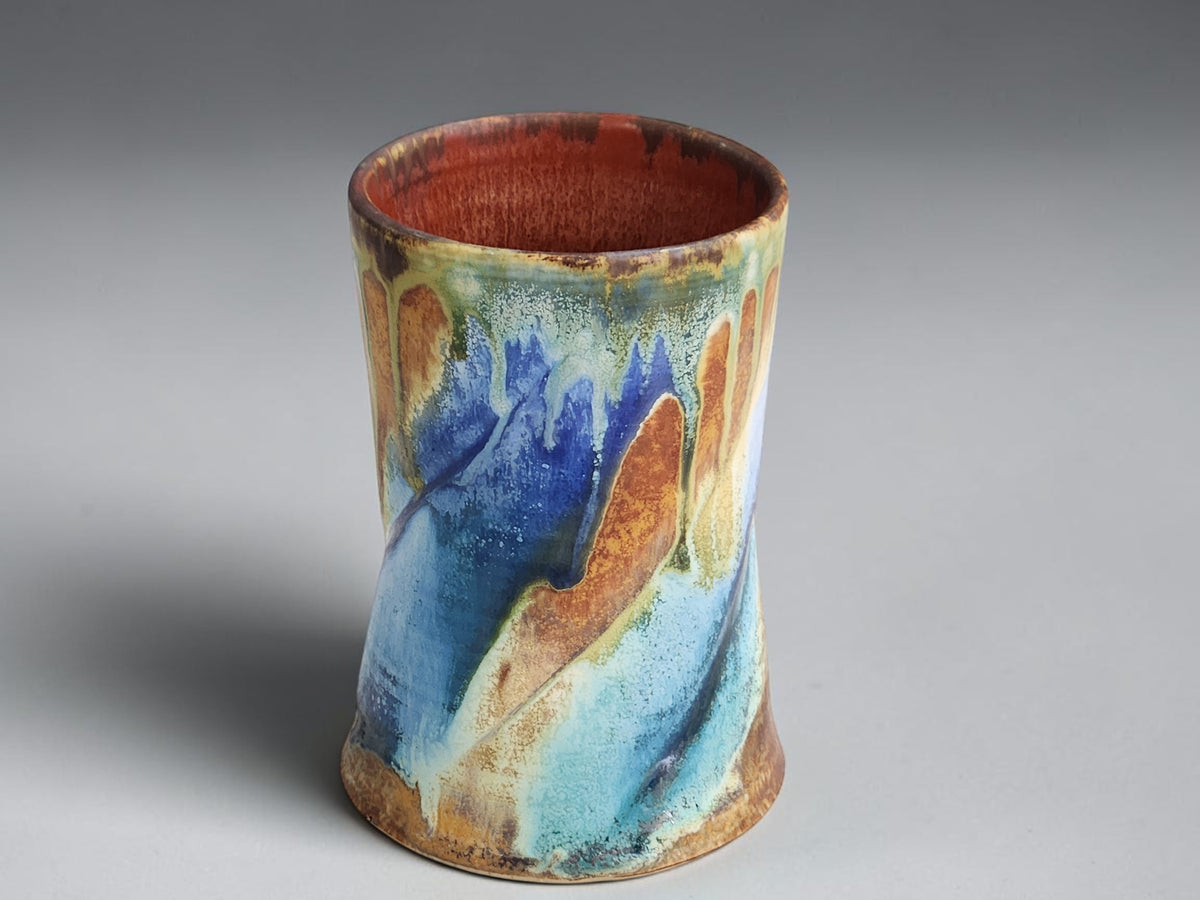 Handcrafted pottery mug with a curved brown handle and rust-brown interior.