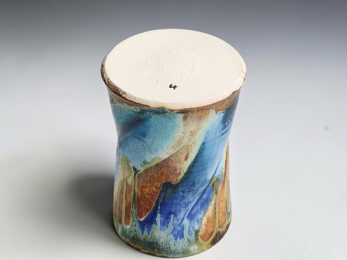 Under side  of soft blue and deep blue glaze flowing across an earthy brown ceramic mug.