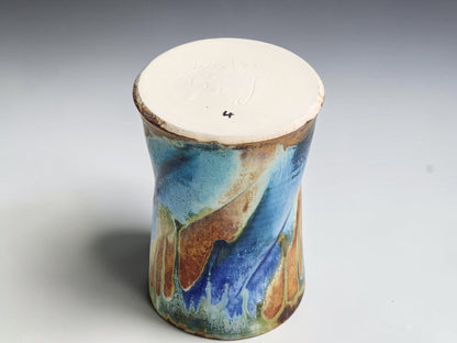 Under side  of soft blue and deep blue glaze flowing across an earthy brown ceramic mug.
