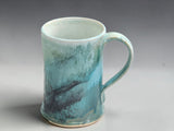 Wheel thrown stoneware mug with flowing aqua and charcoal glaze