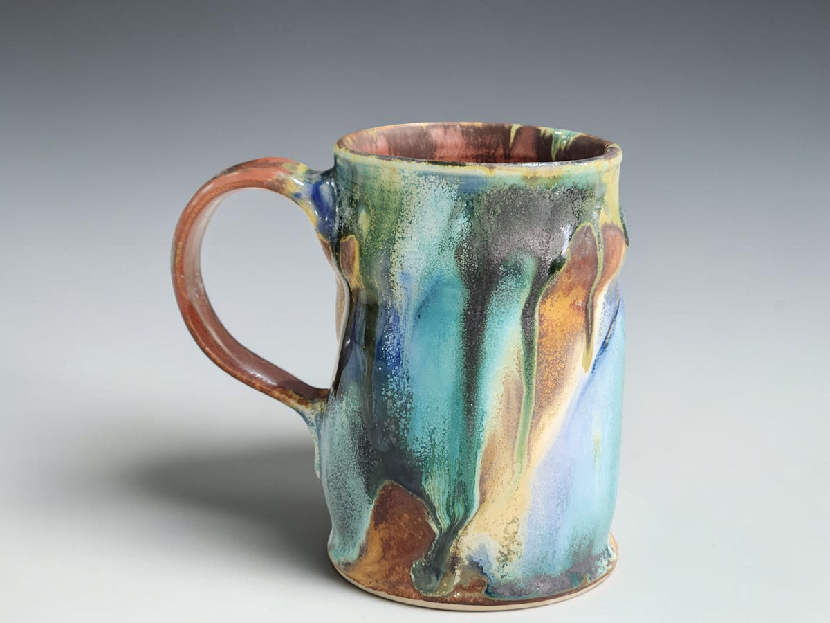 Handmade Bush Creek 350ml pottery mug with flowing teal, blue and earthy brown glaze.