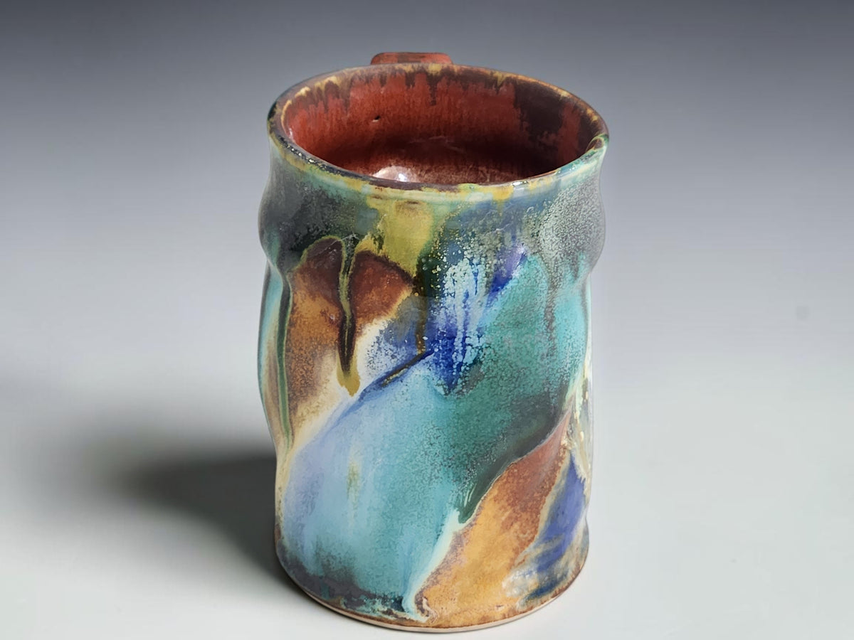 Handmade ceramic coffee mug with a curved brown handle and gently flared rim.
