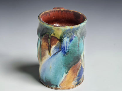 Handmade ceramic coffee mug with a curved brown handle and gently flared rim.