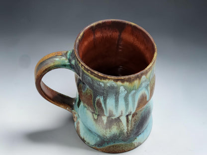 Handmade stoneware mug with flowing ash glaze drips and glossy red brown glazed interior