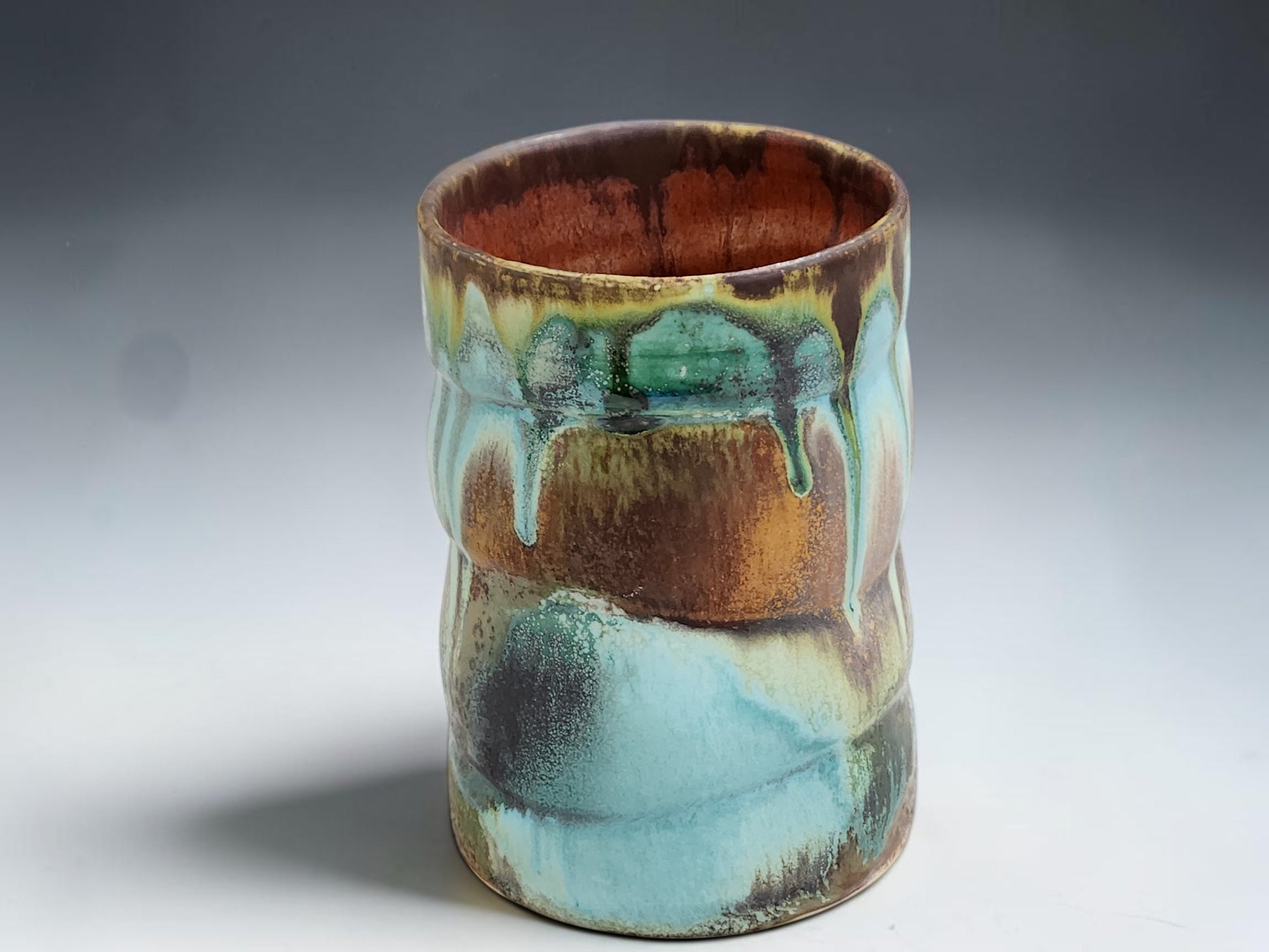 Australian handmade pottery mug with rustic turquoise, brown and rust glaze movement