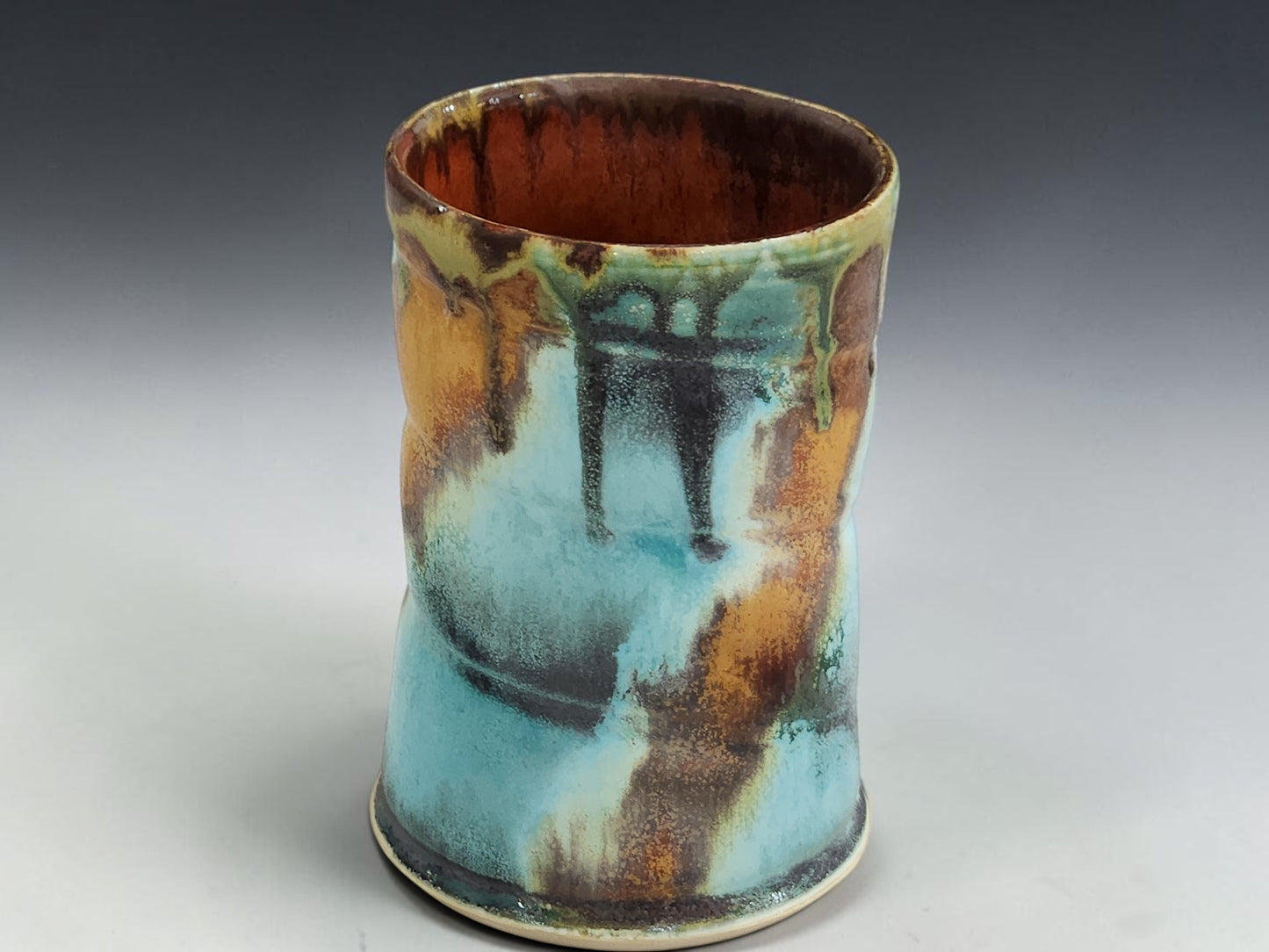 Handmade stoneware mug with flowing ash glaze drips and glossy red brown glazed interior